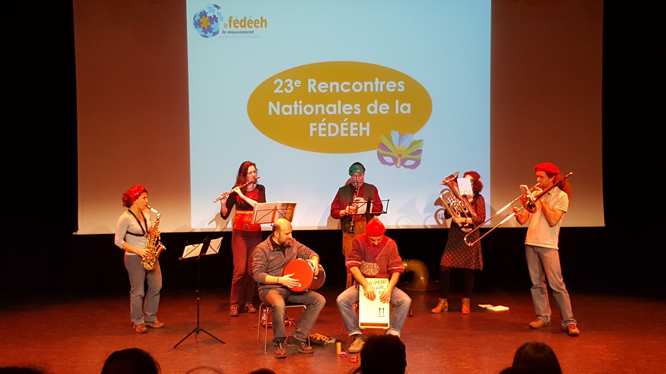 7 jeune qui jouent de divers instruments de musique sur une scene
