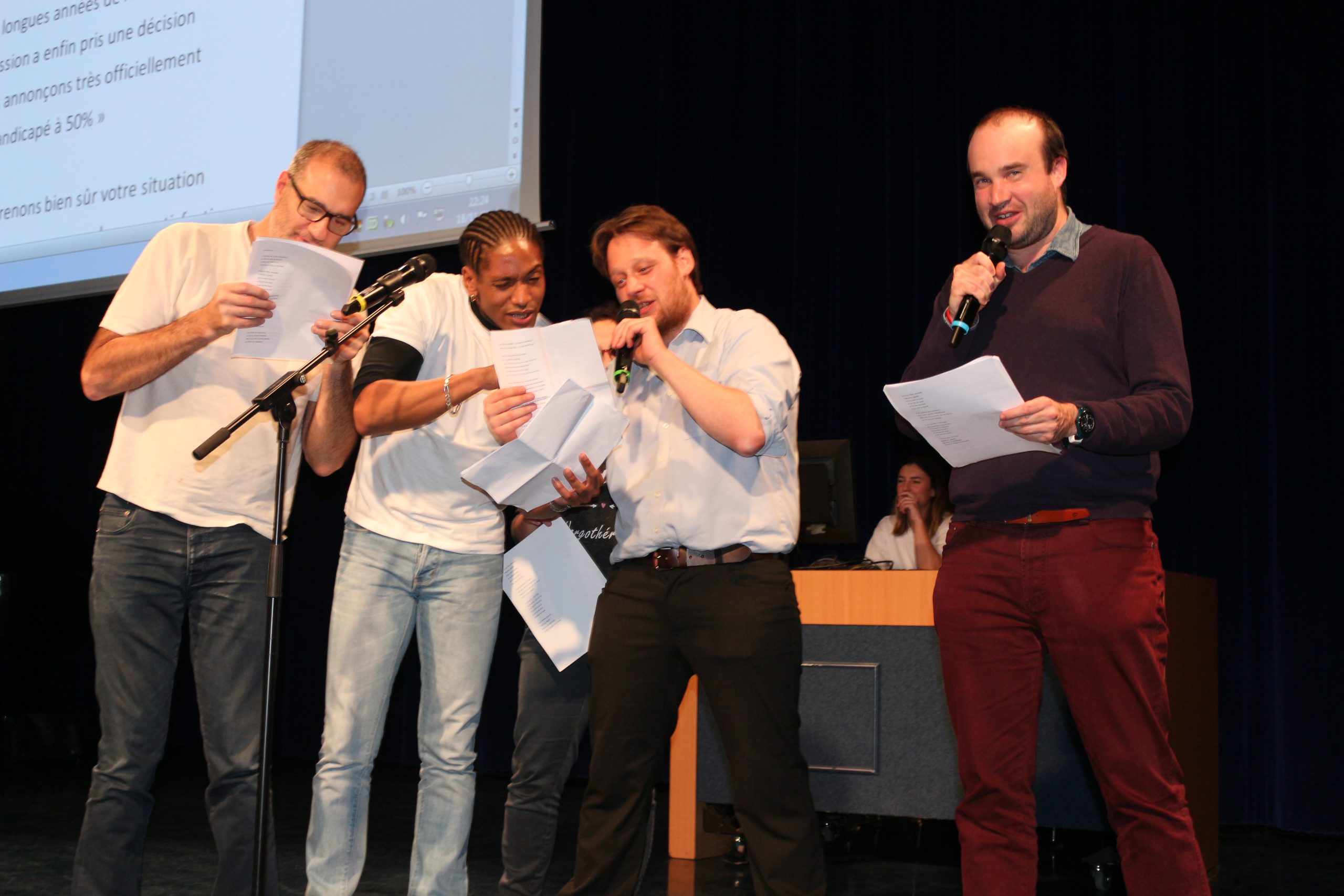 4 hommes sur scène qui lisent un texte au micro