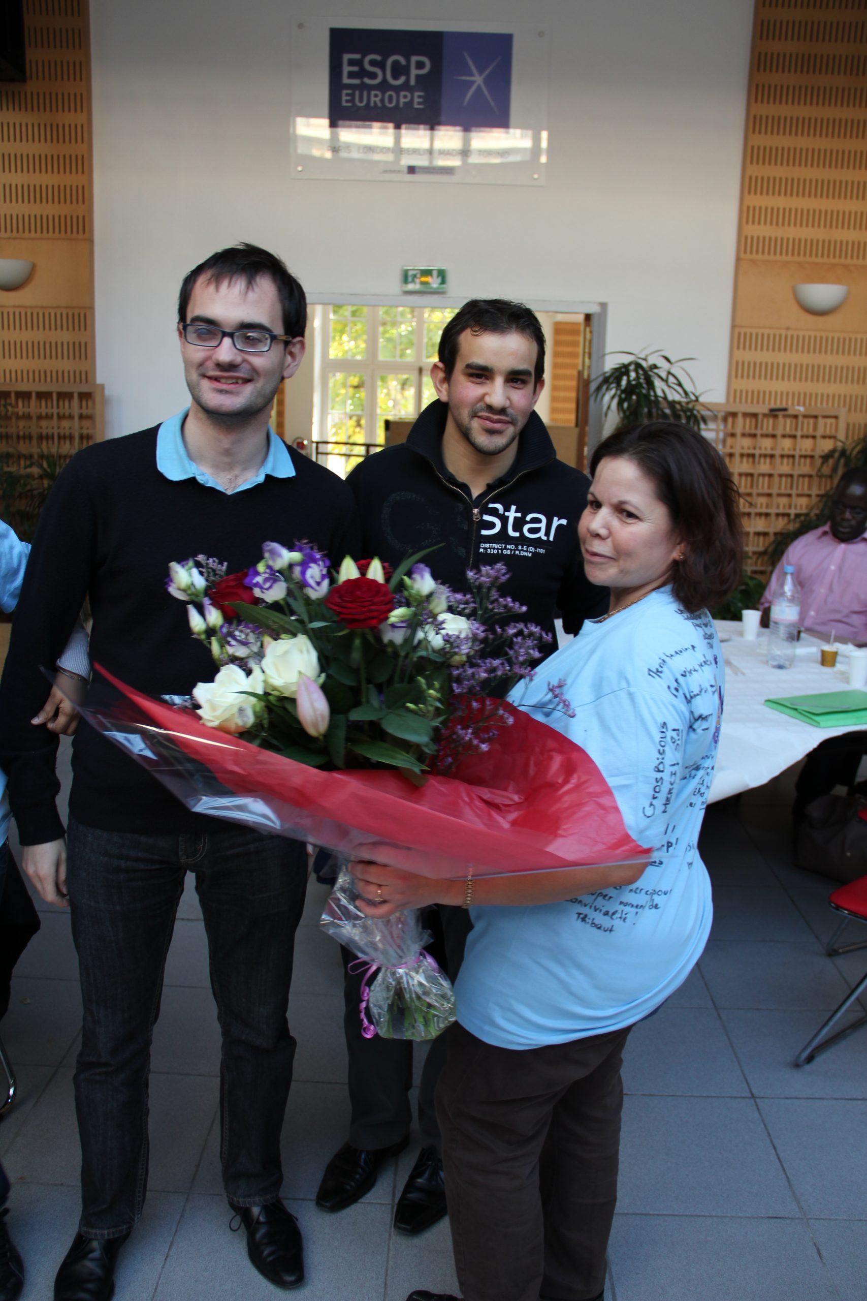 photo de 3 personnes dont une bénévole avec un bouquet de fleurs
